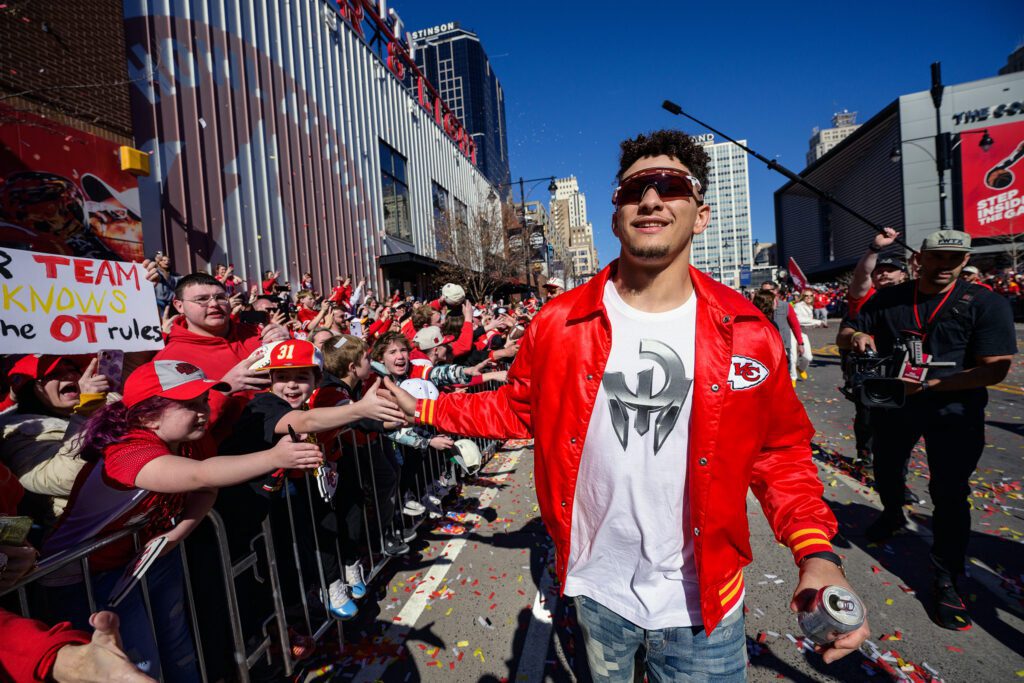 Kansas City Chiefs Quarterback Patrick Mahomes high fives kids while he walks in Super bowl XVIII parade in downtown Kansas City.