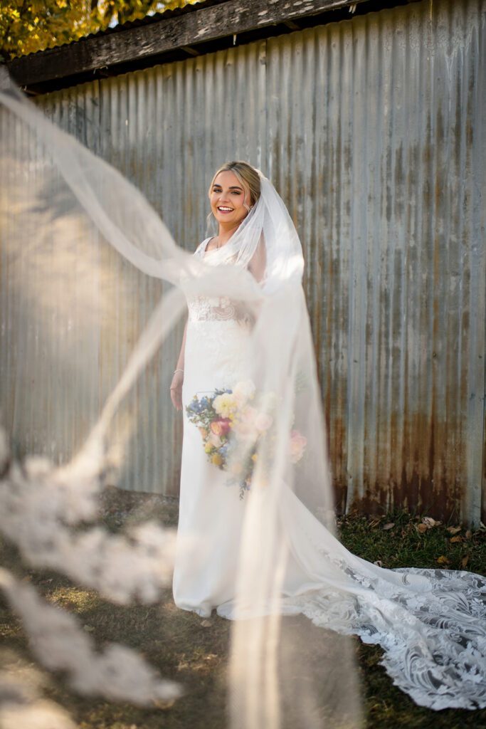 bride in front of rusty tin smiling