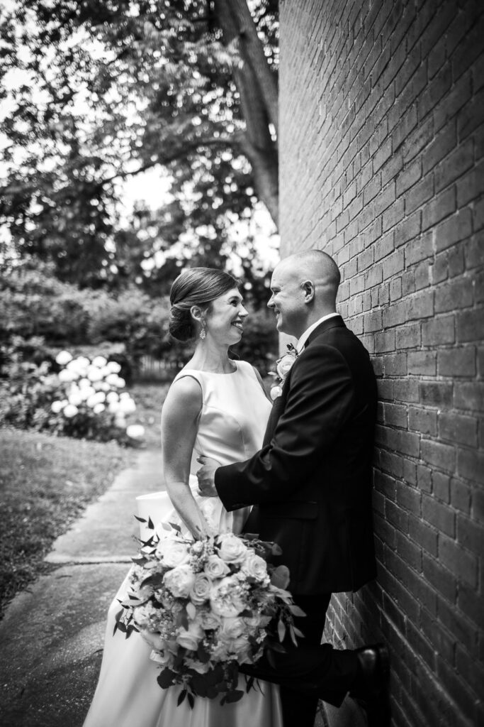 bride and groom leaning against brick wall in garden Washington, MO