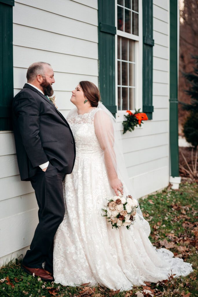 bride and groom leaning against country church