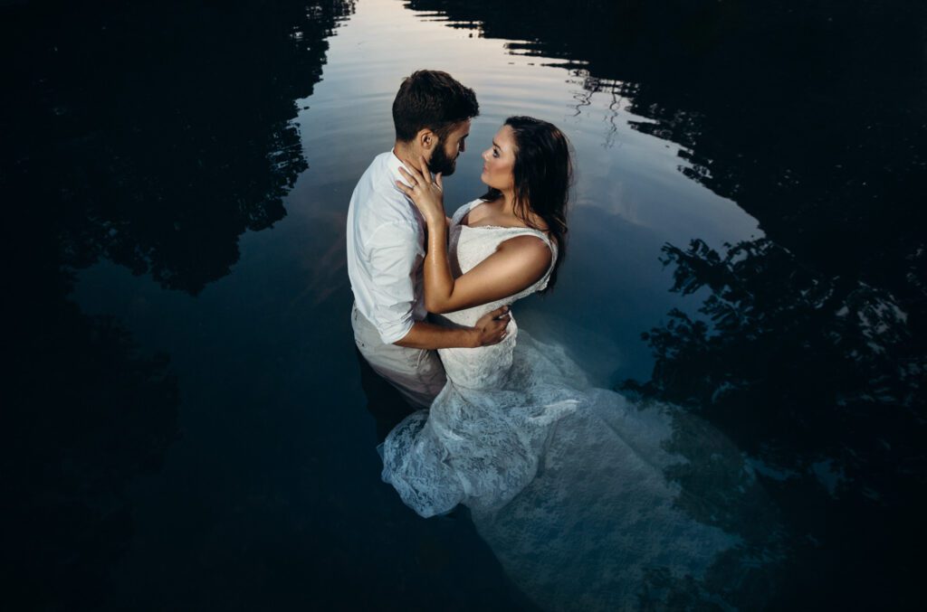 bride and groom looking into each others eyes in lake