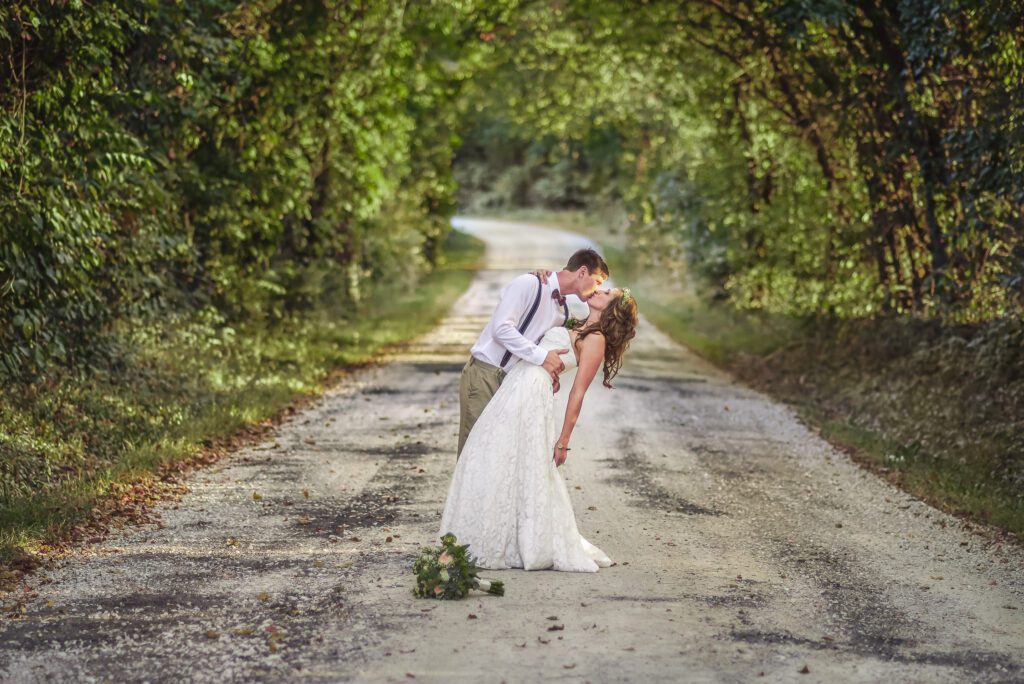 bride and groom kissing on country road