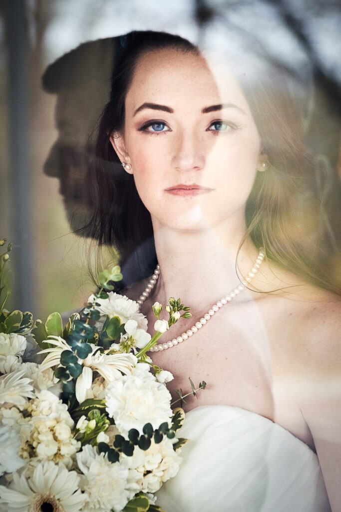 bride looking through grooms reflection in window