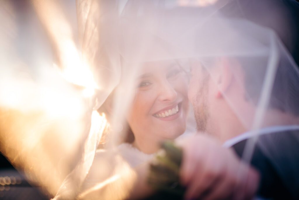 bride looking through veil flying over grooms shoulder Hermann Hill, MO