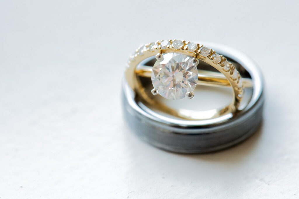 set of engagement rings sitting on husbands wedding band