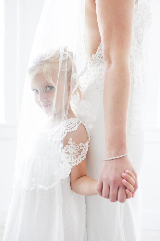 flowergirl under bride's veil holding hands