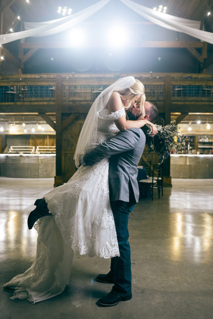 groom holding bride kissing in barn at The Barn III Goodfield, IL