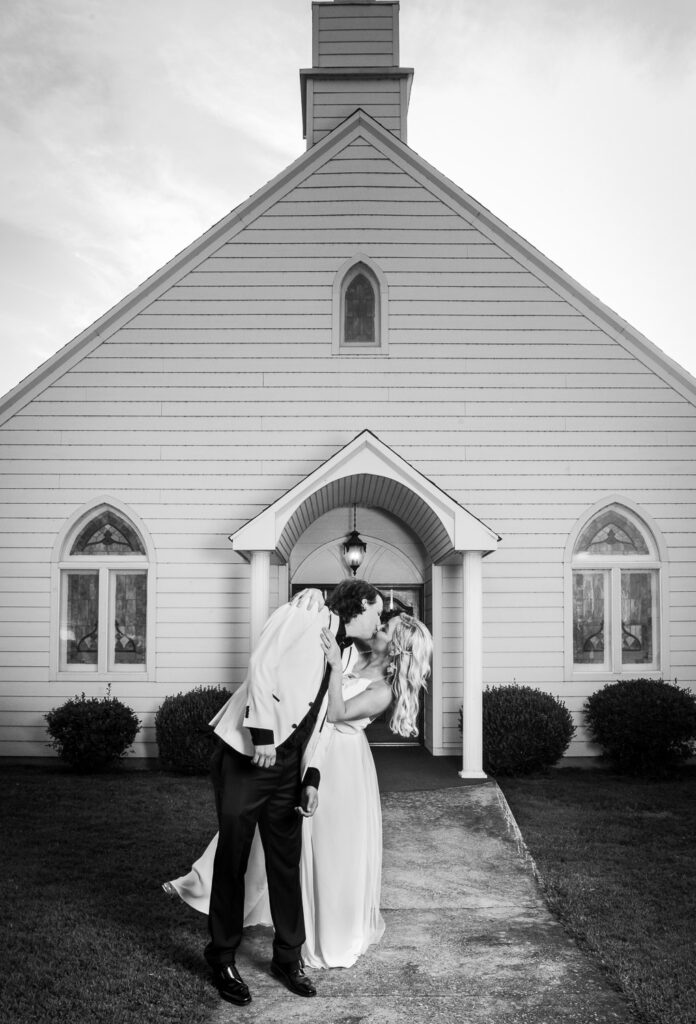married couple kissing in front of chapel