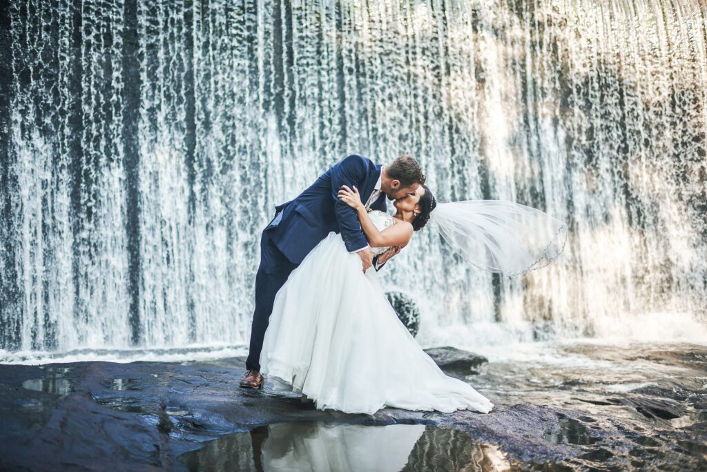Groom dipping Bride in front of waterfall