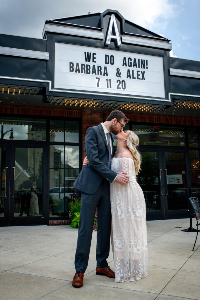 Bride and Groom kiss under marquee sign that says We Do Again.
