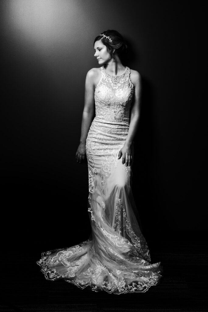 Bride leans on wall wearing wedding dress