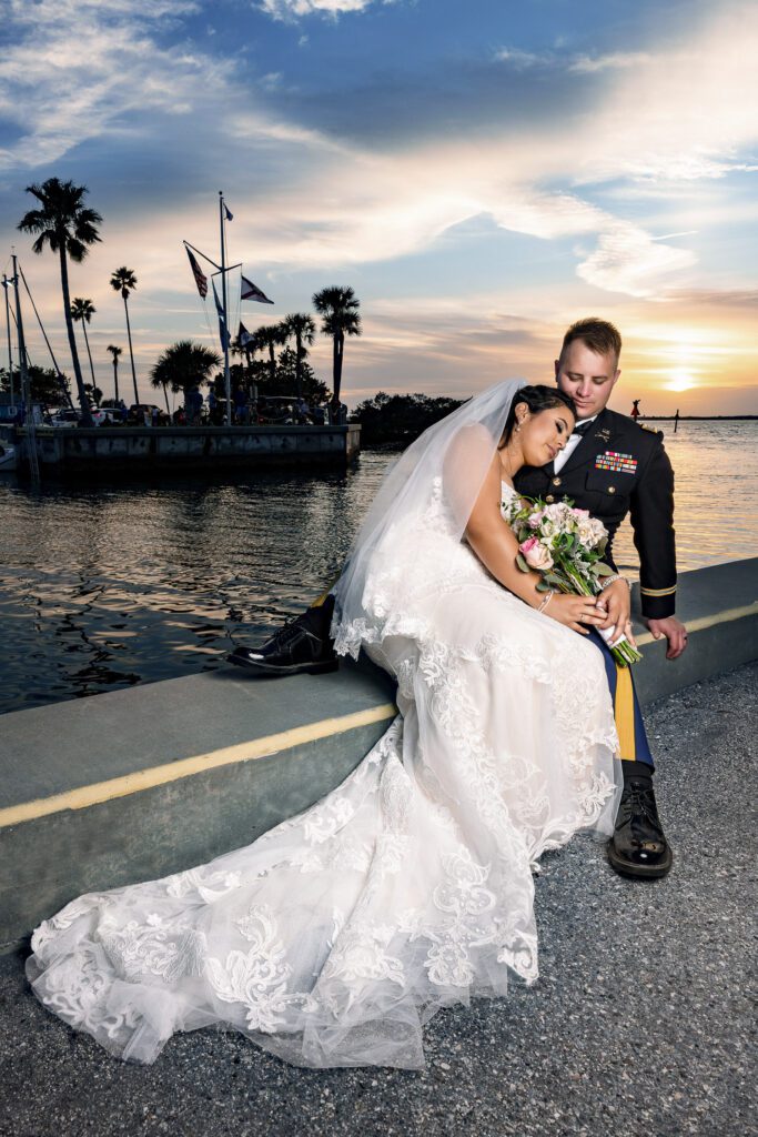 Bride and Groom sitting at pier in front of palm trees in Florida