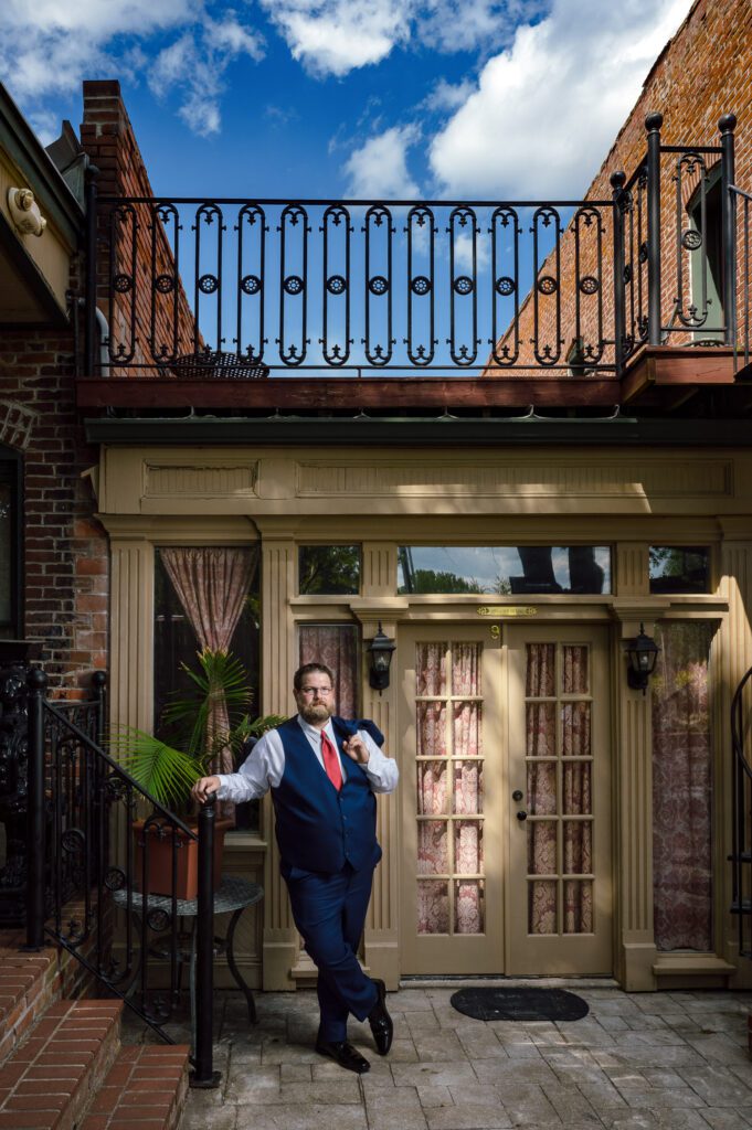 groom leaning on post at vintage hotel