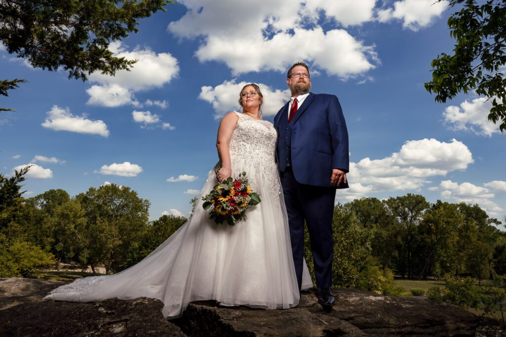 bride and groom on cliff with clouds