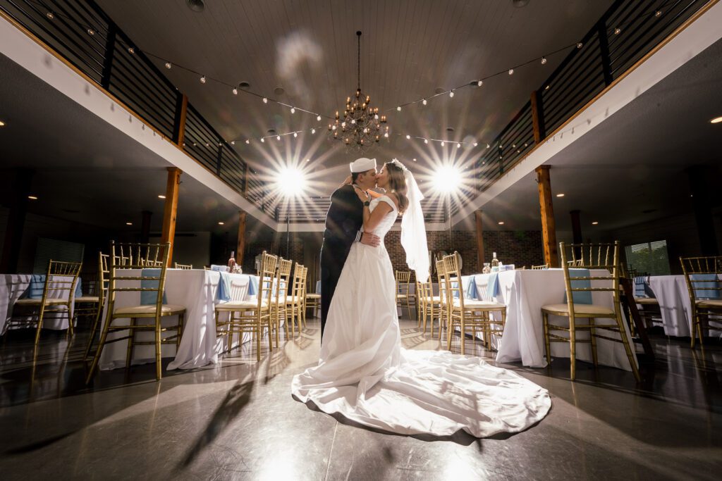 bride and groom kiss in venue with lights