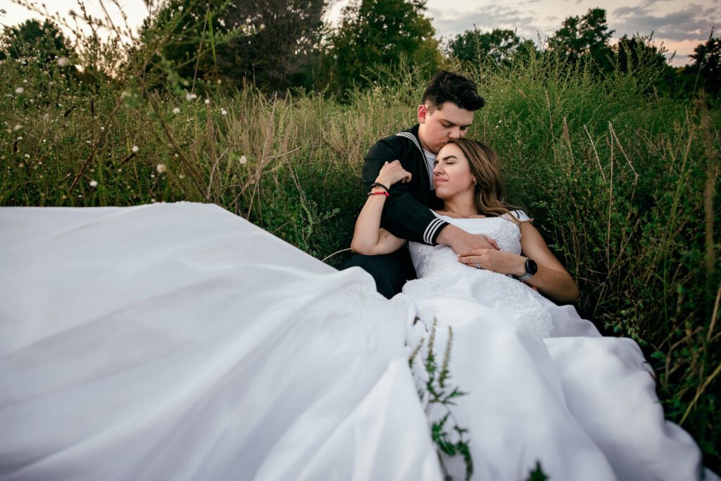 sailor groom hugs bride in field