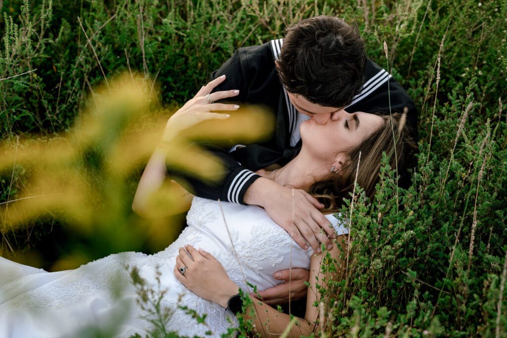 sailor groom kissing bride in field
