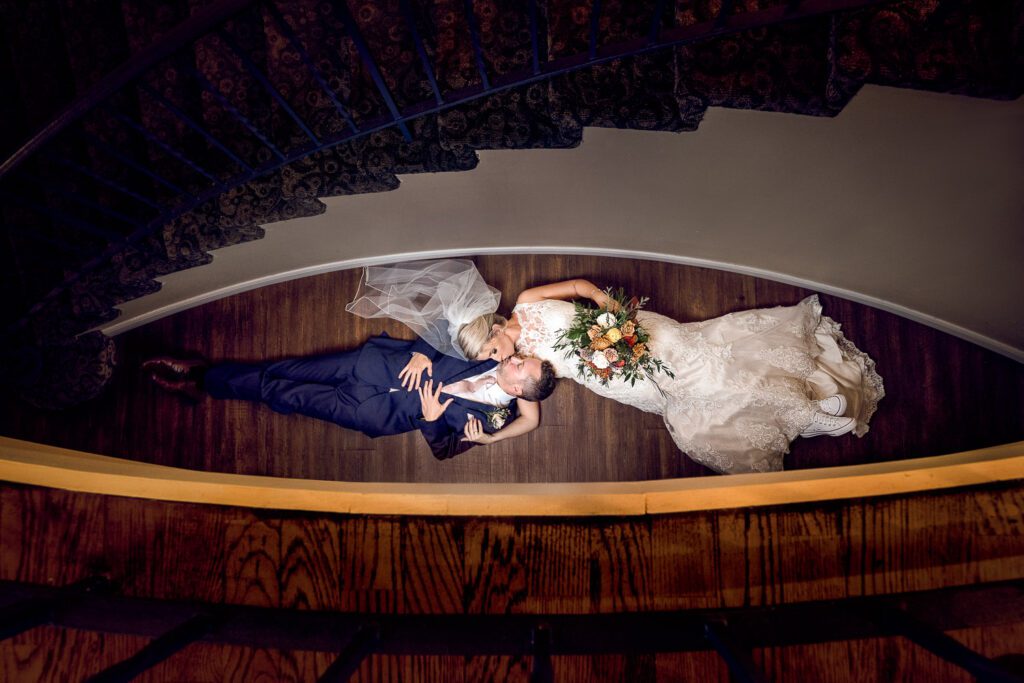 bride and groom laying on floor by staircase