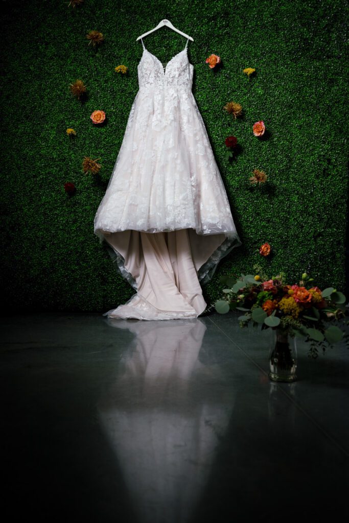 bridal gown on greenery wall and reflection on floor