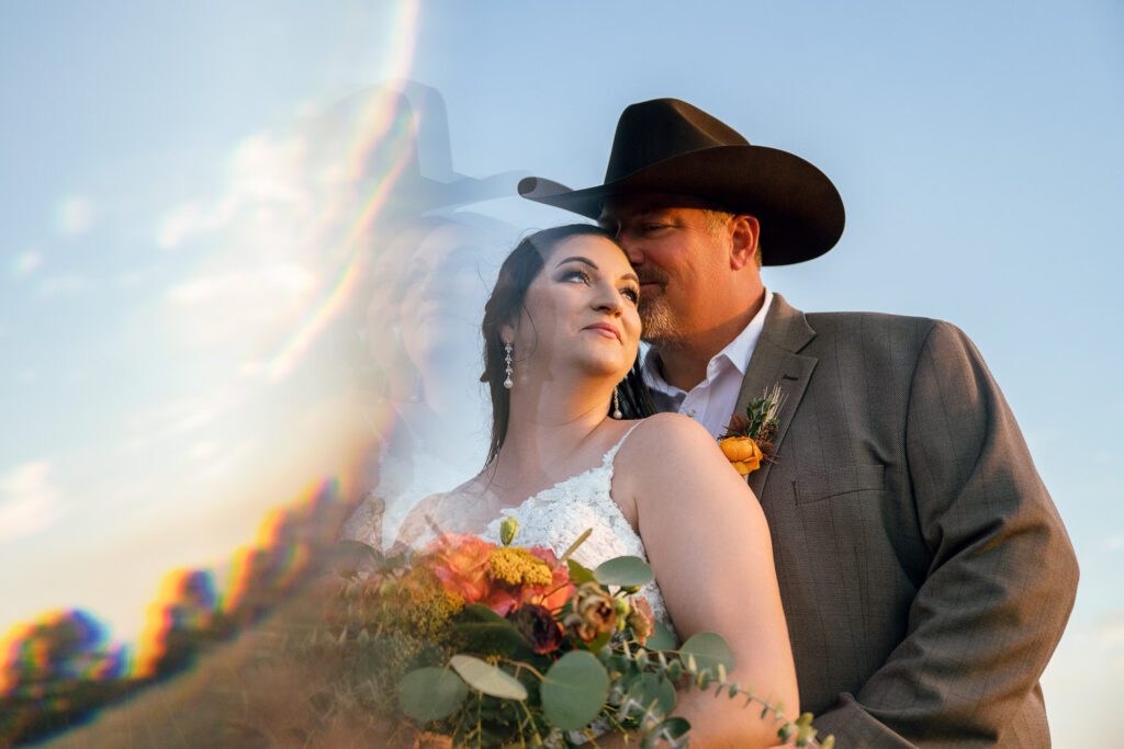 reflective image with bride and groom in field in fall with cowboy hat