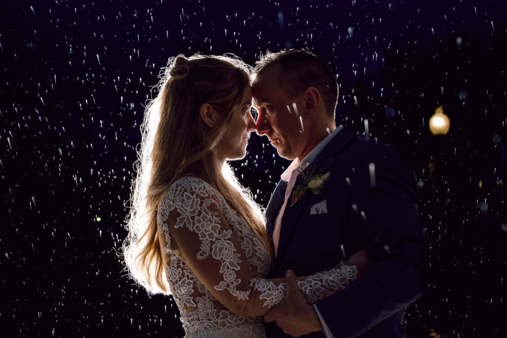 bride and groom hugging in the rain at night
