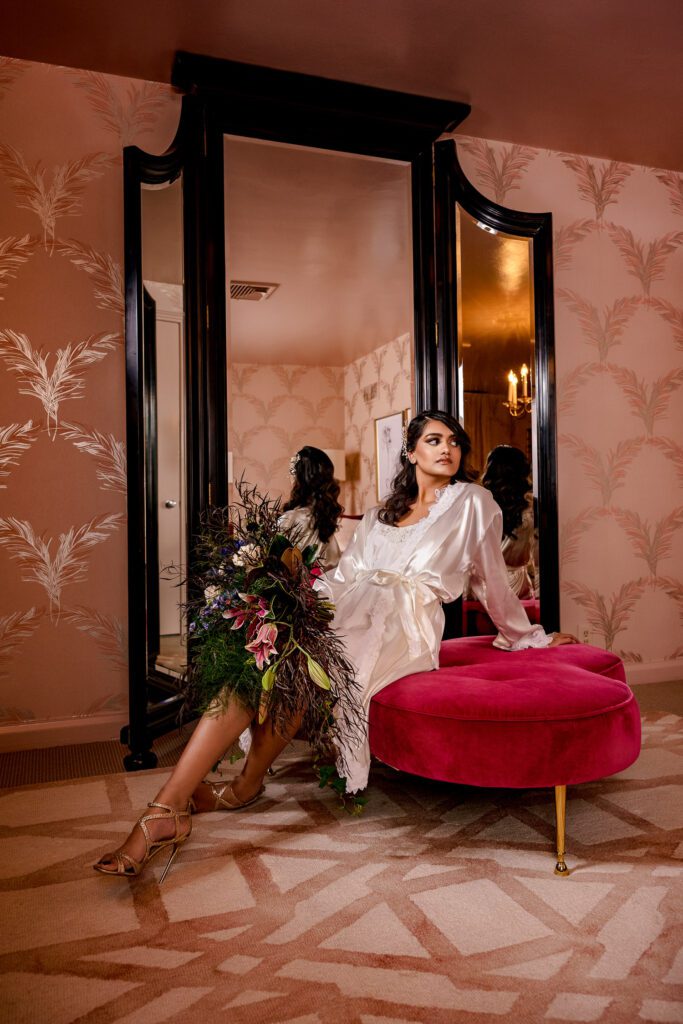 A bride in a silk gown on red cushion with flowers