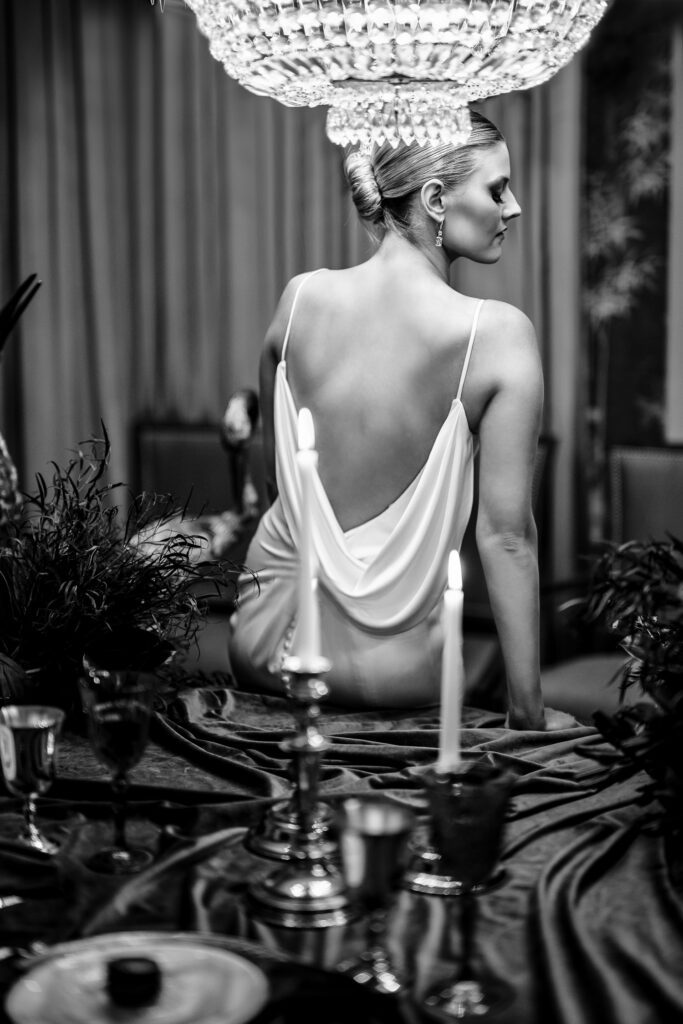 black and white of bride on table set for wedding dinner
