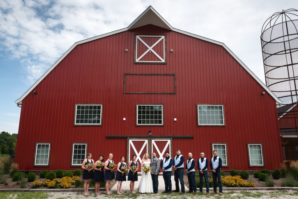 wedding party posing in front of large barn at The Barn III Goodfield, IL