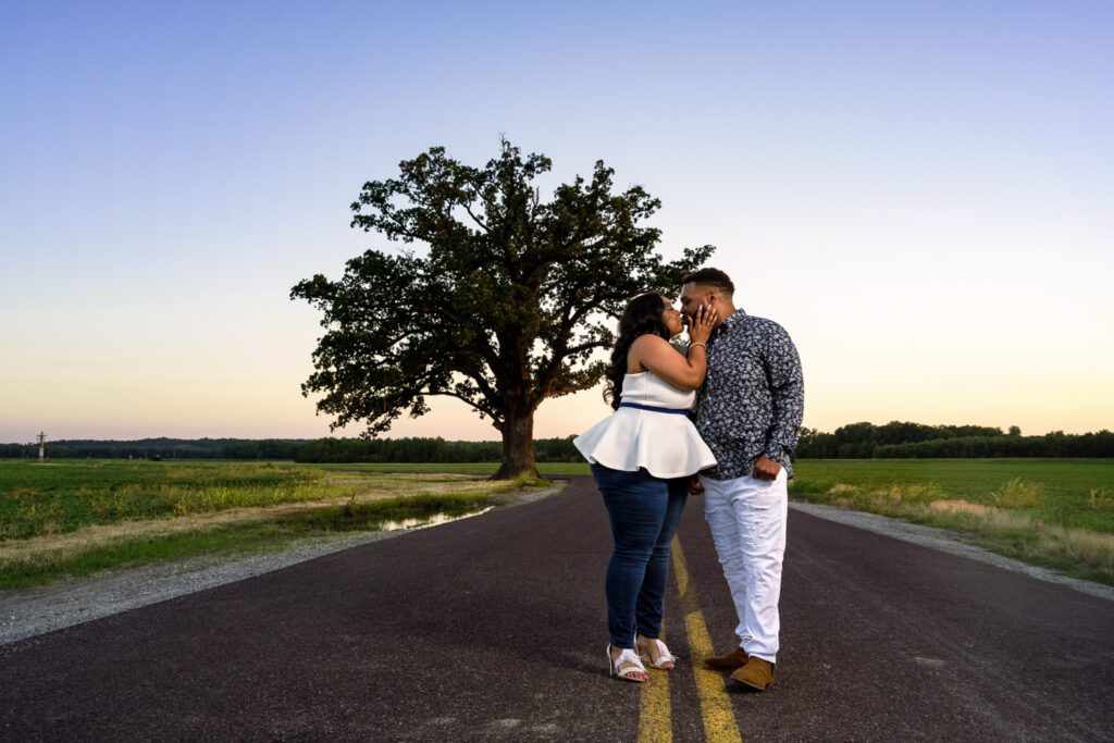 Tierre and Anthony, a black couple, kissing on road in front of big tree near Columbia, Missouri