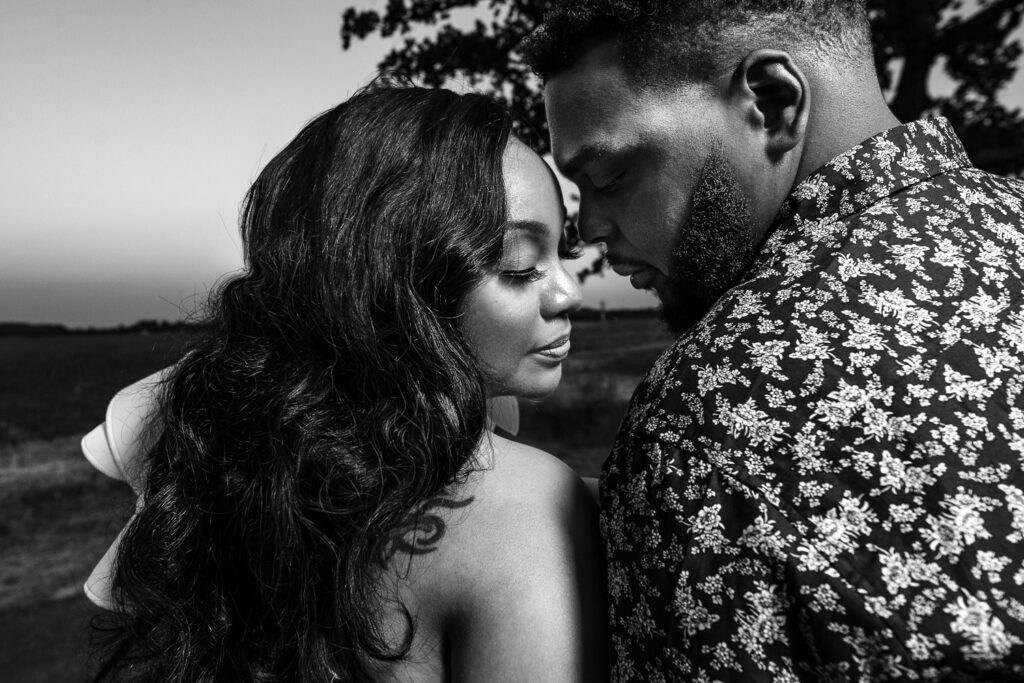 Gorgeous black couple close together during engagement shoot near big tree