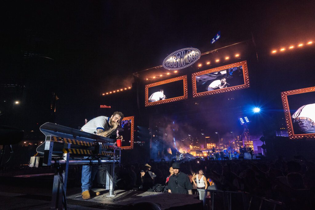 post malone sings into microphone on stage in front of large crowd at Busch Stadium in St. Louis Missouri