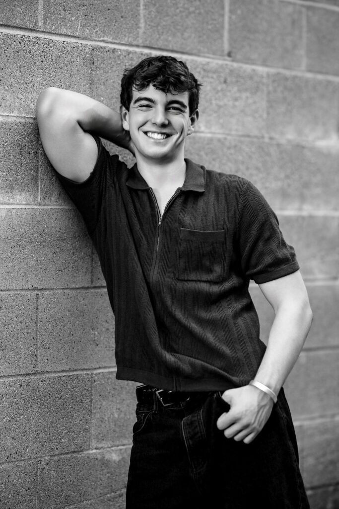 senior guy smiling whilte leaning on wall