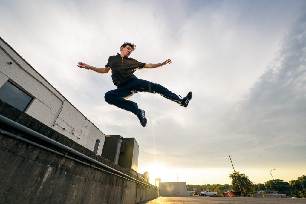 senior guy jumping in air with sunset