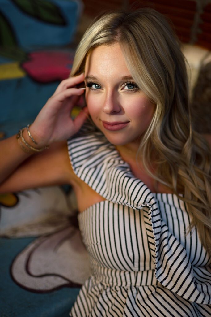 blonde senior girl relaxing on painted steps with patch of sunlight on face
