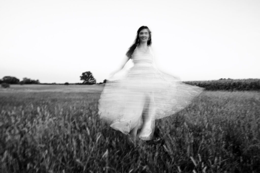 Motion blur senior girl in white dress in field