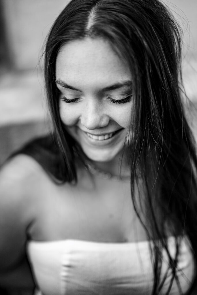 Black and white image of college senior girl smiling as she looks down