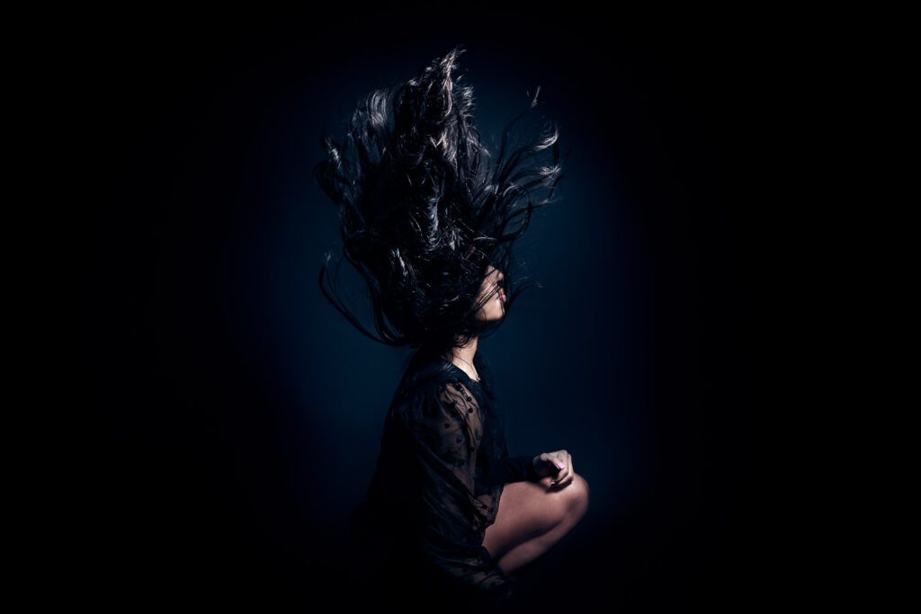 senior girl wearing black flips her dark hair into the air.