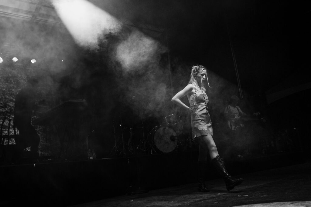 Lennon Stella walks onto stage under spot light.