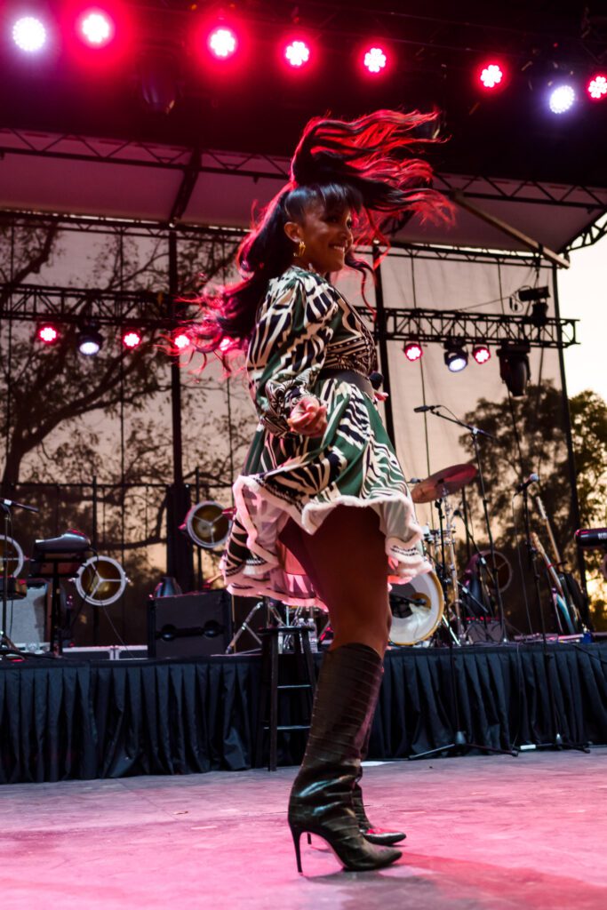 Mickey Guyton swings her hair while dancing under red lights.