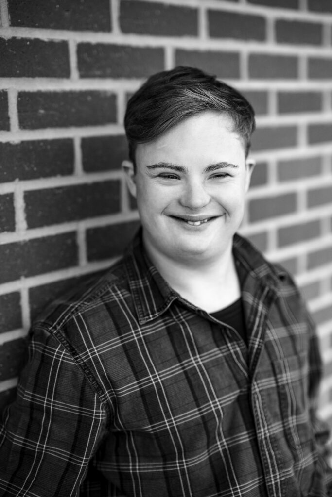 senior guy smiling against brick wall