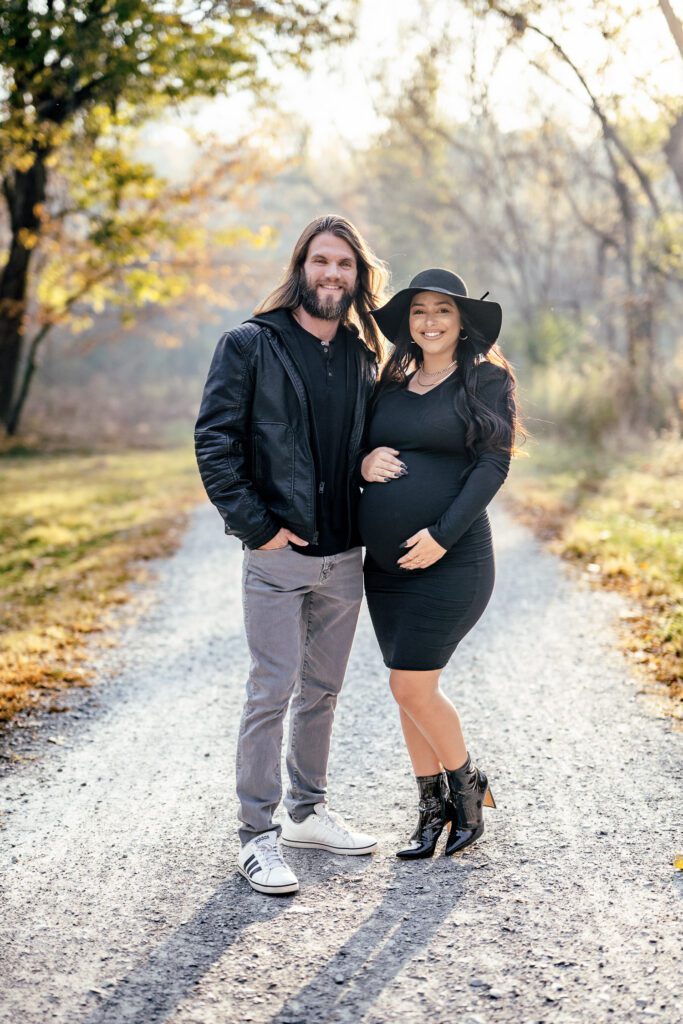 expecting parents wearing black coat, dress, hat during maternity shoot in columbia, missouri.