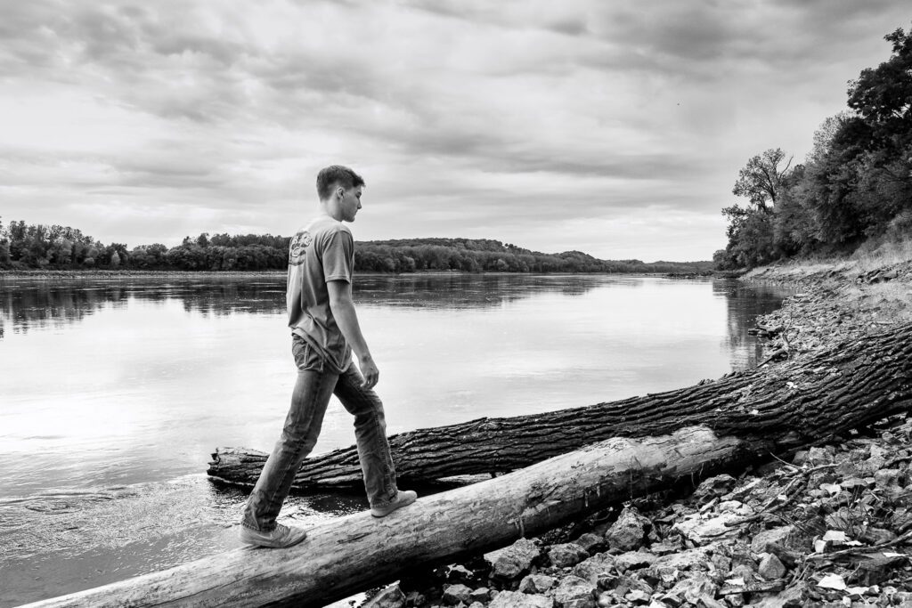 Senior guy walks on downed tree by Missouri River
