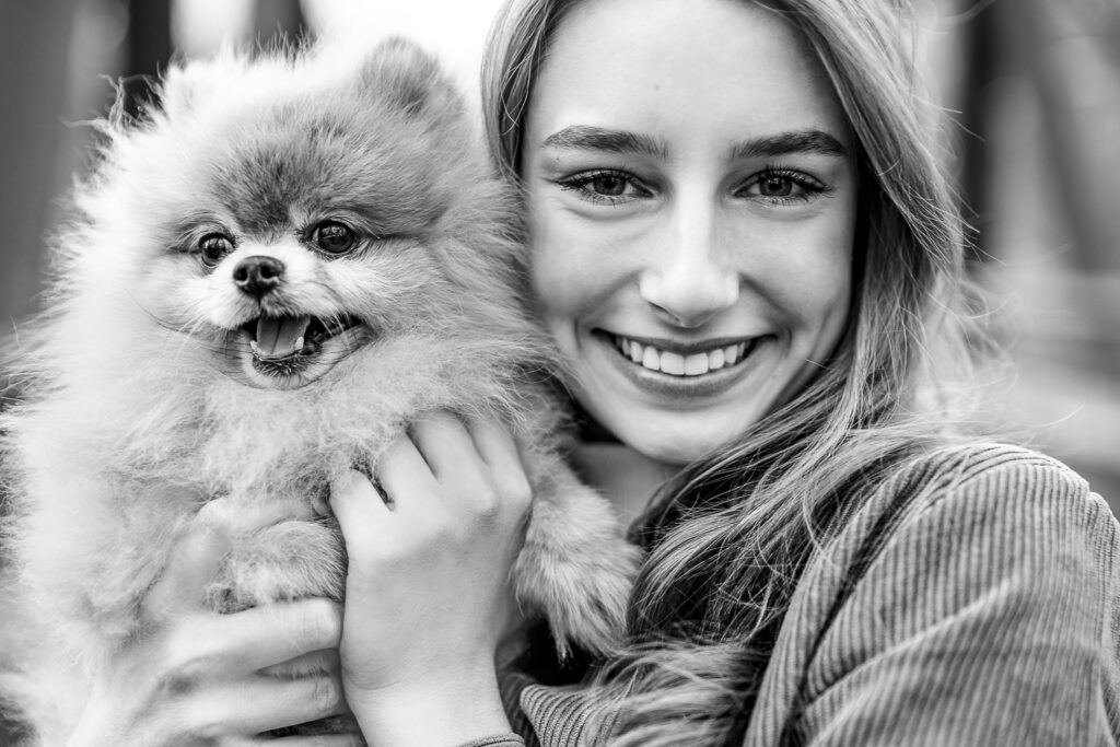 senior girl smiles with fluffy puppy dog