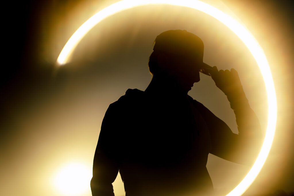 silhouette of senior guy wearing a ball cap with circle of sun light