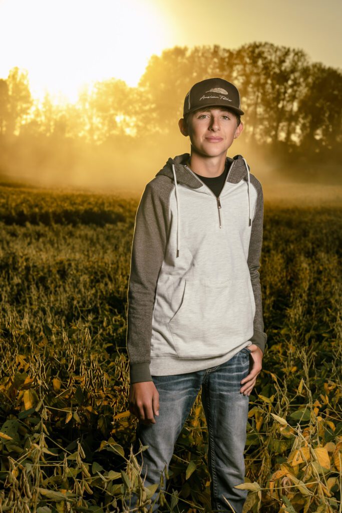 Ashland Missouri senior guy standing in bean field with sun and dust in the background