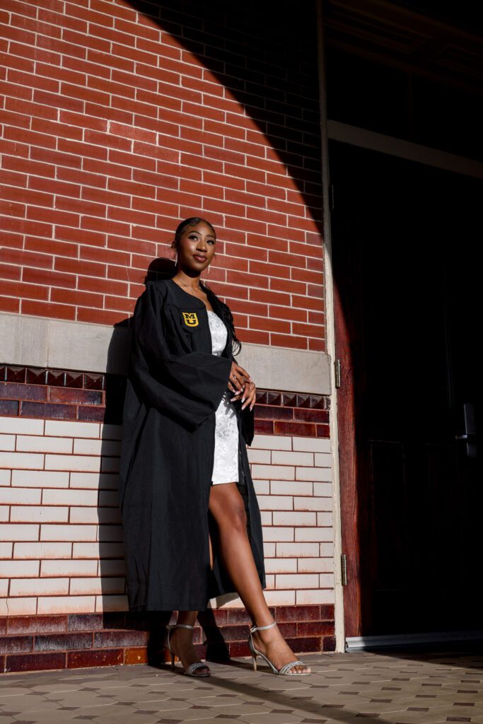 senior college graduate girl leans on brick wall at mizzou