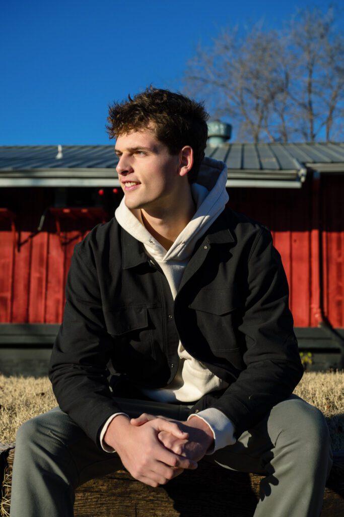 rock bridge high school senior guy wearing hoodie and black jacket in front of red building