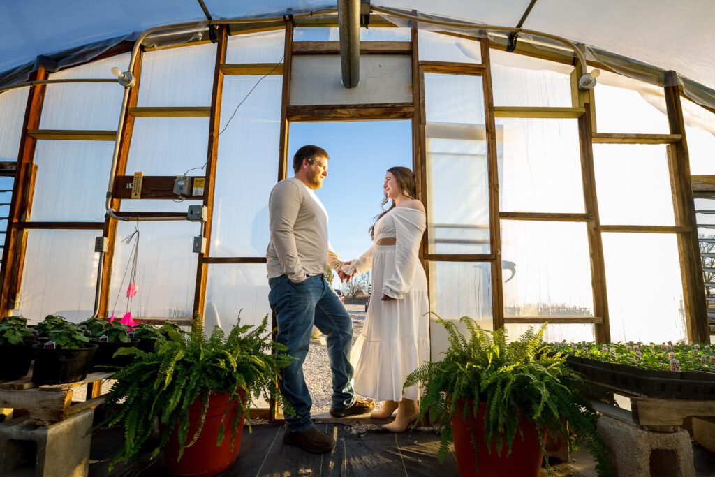engaged couple holding hands in green house doorway