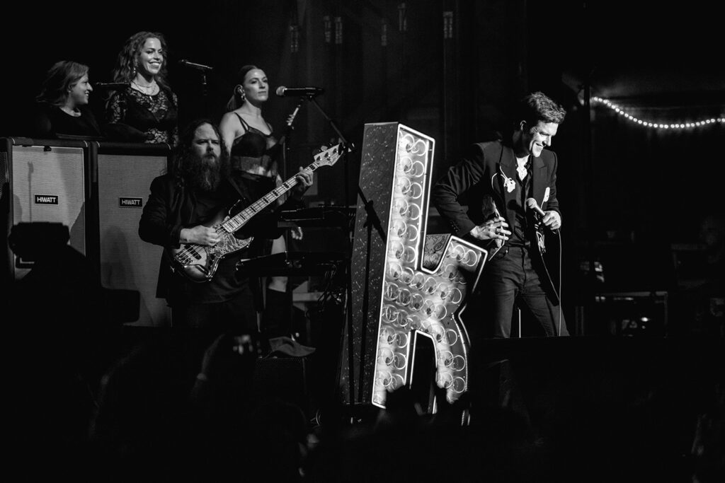 Brandon Flowers looks down while singing on stage