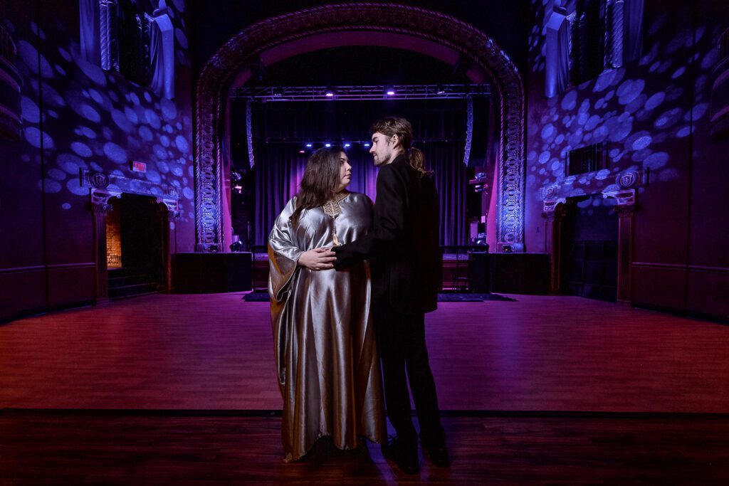 Maternity photo shoot in front of stage at the Blue Note in Columbia Missouri with a silver maternity dress and purple lights.